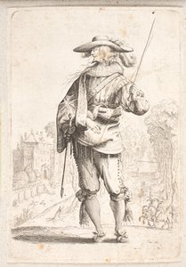 Stehender Soldat von vorne gesehen, aber mit Kopf im linken Profil. Hält einen Stab in der linken Hand