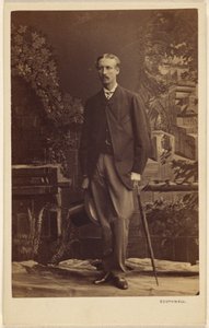 Unbekannter Mann mit Schnurrbart, der einen Zylinder und einen Regenschirm hält, stehend von Southwell Brothers