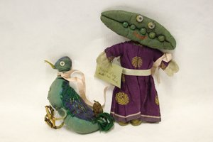 Miss Green Peas Stoffpuppe, Kopf in Form einer Erbsenschote, führt ihre Ente an einem rosa Satinband von Una Maw
