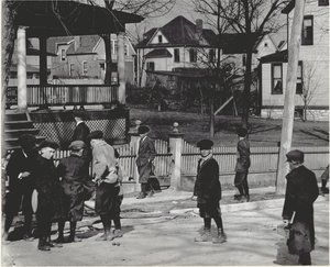 Eine Gruppe von Jungen in Wintermänteln steht auf einer unbekannten Straße entweder vor oder nach einem Schultag.