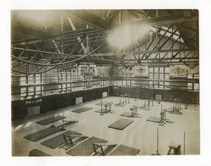 Horizontales Foto des Inneren einer großen Turnhalle. Geräte und Matten sind auf dem Boden verteilt von Unbekannt