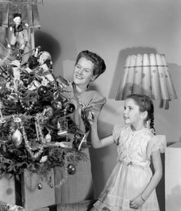Frau und Mädchen schmücken einen Weihnachtsbaum, um 1948