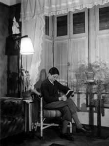 Ein Teenager sitzt in einem bürgerlichen Interieur und liest ein Buch, trägt kurze Hosen und hohe Socken. 1915. Historisches Foto, Frau liest, ca. 1915. von Unbekannter Künstler
