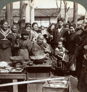 Ein Straßenkünstler mit einem Affen, der die Menge unterhält, Kobe, Japan, 1896 von Underwood and Underwood