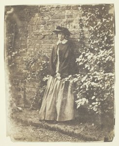 Mrs. Craik lehnt an Wand und Büschen