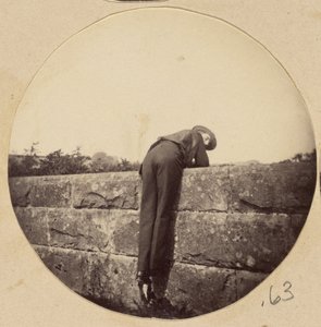 [Mann mit Hut über eine Steinmauer gebeugt] von Unknown artist