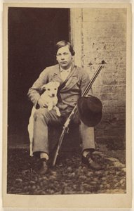 Mann sitzt mit einem weißen Hund, einem Gewehr und einem Hut auf seinem Bein