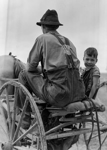 Bauer und lächelnder Junge fahren auf dem Sitz eines pferdegezogenen Wagens in West Virginia