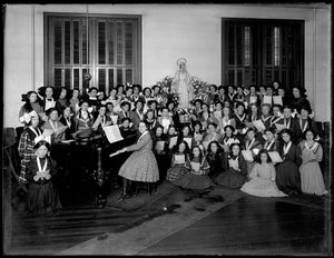 Gruppenporträt einer Mädchenchor-Klasse, die sich um ein Klavier versammelt und Noten hält, wahrscheinlich im römisch-katholischen Waisenhaus in Kingsbridge, Bronx, ca. 1911 von William Davis Hassler