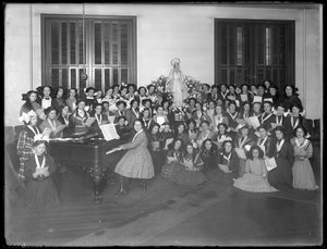 Gruppenporträt einer Mädchenchor-Klasse, die sich um ein Klavier versammelt und Notenblätter hält, wahrscheinlich im römisch-katholischen Waisenhaus in Kingsbridge, Bronx, um 1911 von William Davis Hassler