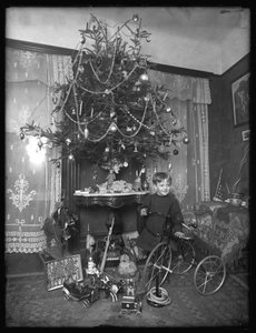 Seymour-Junge posiert mit Dreirad neben Weihnachtsbaum im Salon, Weihnachten 1912
