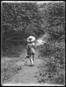 William Gray Hassler mit Strohhut und Latzhose, trägt Angelrute und Korb, geht allein einen Pfad im Wald entlang, 20. August 1911 von William Davis Hassler