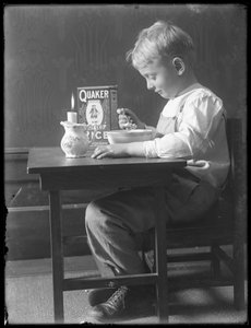 William Gray Hassler sitzt an einem kleinen Tisch und isst eine Schüssel Quaker Puffreis, ca. 1912 von William Davis Hassler