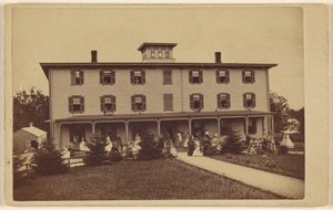 Ansicht eines Hauses mit zahlreichen Personen auf der Veranda und dem Rasen von Yeaw and Company