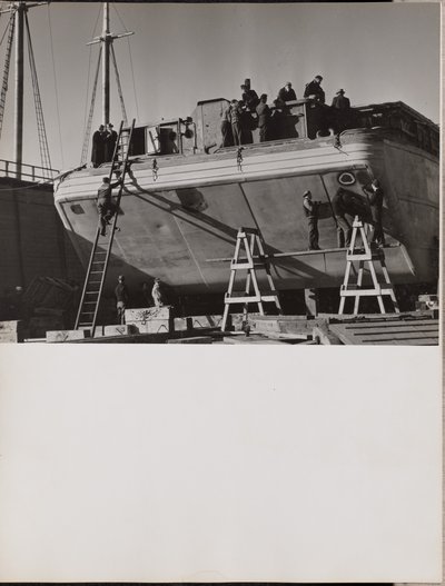 Eine Gruppe von Männern arbeitet an einem angedockten Boot von Arnold Eagle