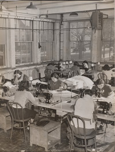 [Frauen sitzen an Schreibtischen und arbeiten an Nähmaschinen] von Arnold Eagle