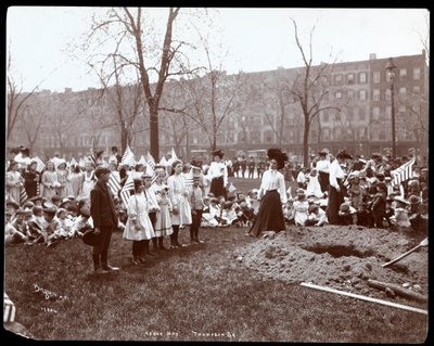Erwachsene und Kinder mit Fahnen stehen um ein frisch gegrabenes Loch für eine Baumpflanzung am Arbor Day im Tompkins Square Park, New York, 1904 von Byron Company