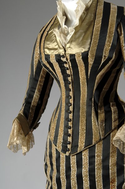 Abendkleid, ca. 1884 (teilweise seitliche schräge Ansicht). Seidensatin und geschnittener Samt, Spitze, Seidenfadenquasten und Fransen. Charles Frederick Worth, Frankreich. von Charles Frederick Worth