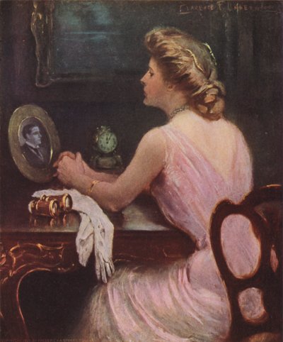 Frau sitzt an ihrem Schminktisch und betrachtet ein Foto eines Mannes, möglicherweise ihres Mannes oder Liebhabers von Clarence F. Underwood