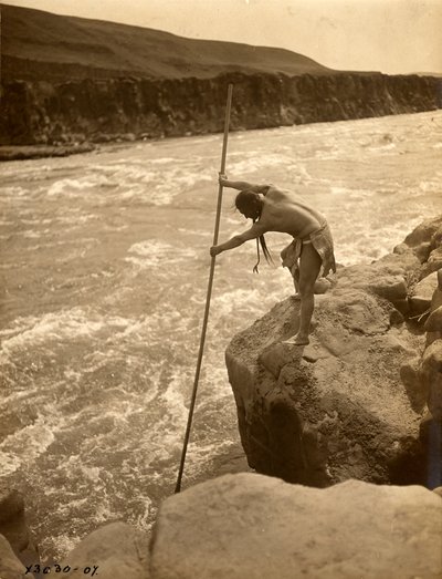 Tlakluit-Indianer, stehend auf Felsen, fischend mit Dip-Netz, ca. 1910 (s/w Foto) von Edward Sheriff Curtis
