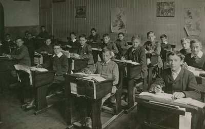 Männliche Schüler sitzen während einer Unterrichtsstunde an ihren Schreibtischen von English Photographer