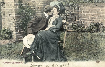 Mann stiehlt einen Kuss von einem Mädchen auf einer Gartenbank von English Photographer