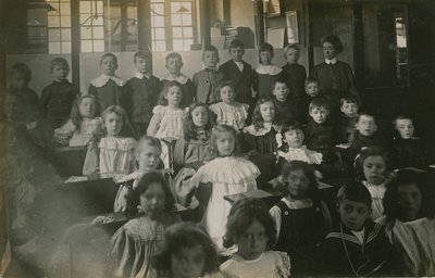 Schüler sitzen an ihren Schreibtischen und posieren für ein Porträt von English Photographer