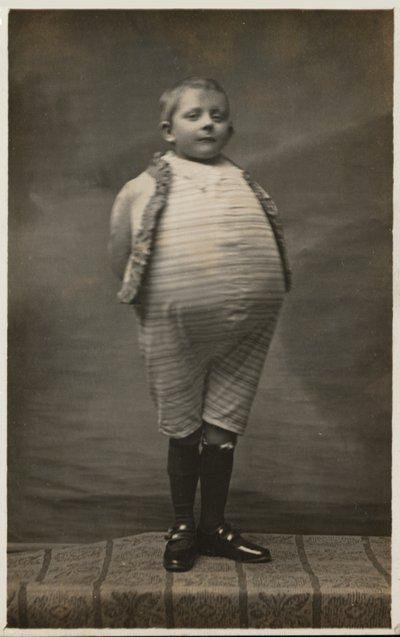 Schuljunge, verkleidet mit einem sehr großen Bauch (s/w Foto) von English Photographer