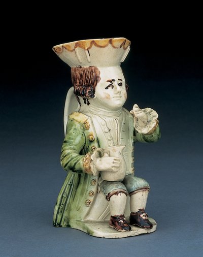 Trinker Toby Krug, sein Hut mit braunem und gelbem gewelltem Rand, sein eingeschnittenes braunes Haar en queue und mit einer weißen Rosette, sitzend mit einem Balusterkrug auf seinem Knie, ca. 1770 von English School