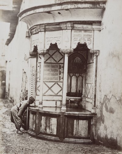 Ein Mann trinkt aus einem Eckbrunnen auf einer Straße in Damaskus, Syrien von Félix Bonfils