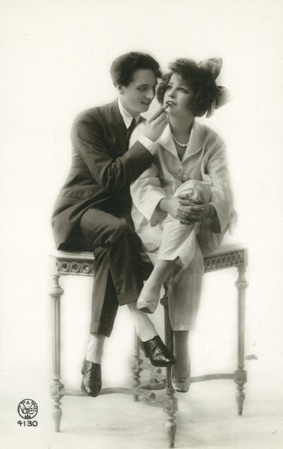 Androgyn Mann im Anzug, der Lippenstift auf die Lippen eines Mädchens im Pyjama aufträgt von French Photographer