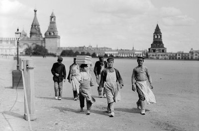 Russische Moskauer Arbeiter marschieren zur Arbeit mit den Zinnen der Kreml-Festung im Hintergrund von Gilbert H. Grosvenor