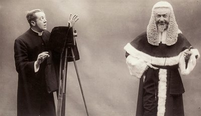 Ein Mann in Soutane richtet die Linse seiner Kamera auf einen Mann, der wie ein Papst gekleidet ist von Rotary Photographic Co Ltd