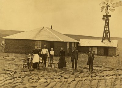 Familie von Siedlern vor ihrem Sodenhaus mit einer Windmühle auf dem Dach des angrenzenden Gebäudes in Custer County, Nebraska, ca. 1885 von Solomon D. Butcher