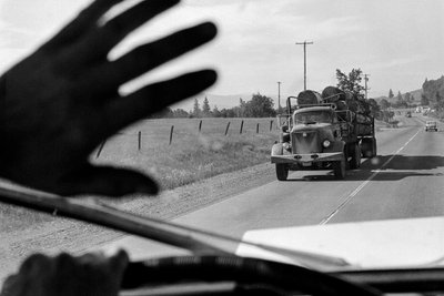 Fahrer in einem Holztransporter winkt einem anderen Holztransporter zu von Ted Spiegel