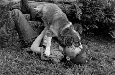 Junger Mann spielt mit seinem Hund vor ihrer Blockhütte in Palmer, Alaska von Ted Spiegel