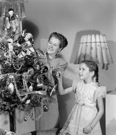 Frau und Mädchen schmücken einen Weihnachtsbaum, um 1948 von Unbekannt