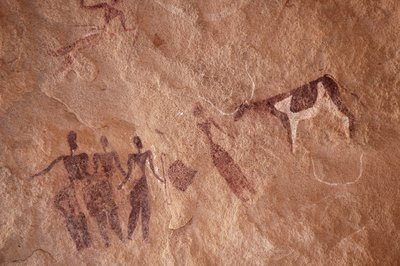 Felskunst, Vorgeschichte: Felsmalerei einer Gruppe von Figuren und einer zweifarbigen Kuh mit großen Hörnern in einem verzierten Schutzraum im Uweinat-Massiv, Ägypten. (Zeitraum von 8000 bis 3000 v. Chr.). Fotografie von Unbekannt