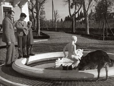 Gino Bartali mit zwei Kindern und einem Hund in der Nähe eines Brunnens von Unknown photographer