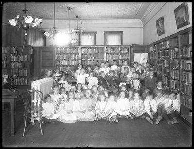Gruppenporträt von Kindern im Lesesaal einer nicht identifizierten Filiale der Queens Borough Public Library, um 1910 von William Davis Hassler