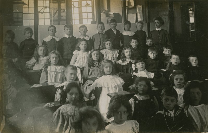 Schüler sitzen an ihren Schreibtischen und posieren für ein Porträt von English Photographer