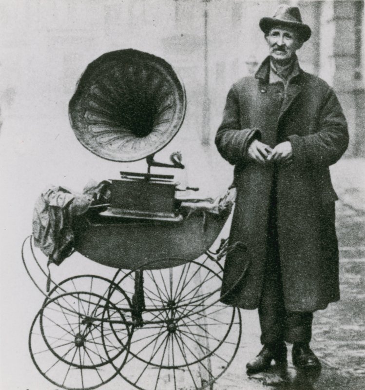 Unbetitelte Fotografie eines Mannes mit einem Phonographen in einem Kinderwagen von English Photographer