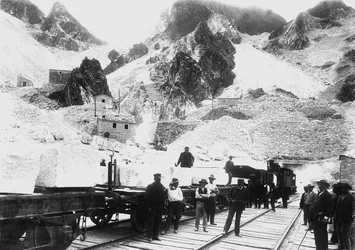 Ausgräber vor einem Eisenbahnzug, beladen mit Marmorblöcken in Ravaccione, in den Apuanischen Alpen