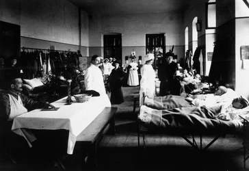 Dekorierter Salon in einem Krankenhaus mit Kriegsverwundeten, Ärzten, Rotkreuzschwestern und Besuchern