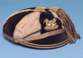 Blau-weiße segmentierte Fußballkappe mit Metalldrachenabzeichen und Goldquaste