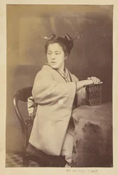 Sitzende japanische Frau mit einem Cartes-de-Visite-Album an einem Tisch