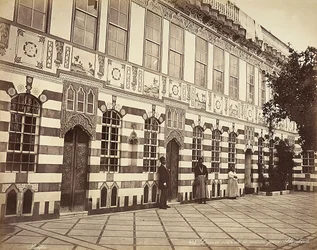 Der Hof eines jüdischen Hauses in Stambouli, Syrien. Drei Bedienstete sind in der Nähe der Wände des Gebäudes zu sehen