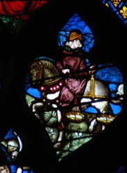 Das westliche Rosenfenster zeigt eine Szene aus dem Buch der Offenbarung: Ein Reiter (sein Pferd nicht schwarz wie im Text) trägt die Waage, um Weizen und Gerste zu messen (6:5).