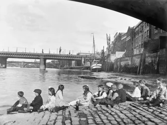 Kinder auf dem gepflasterten Damm unter der Southwark-Brücke, London, ca. 1930