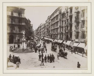 Ansicht der Via Roma in Neapel mit einer Statue, Geschäften, Pferdekutschen und Passanten